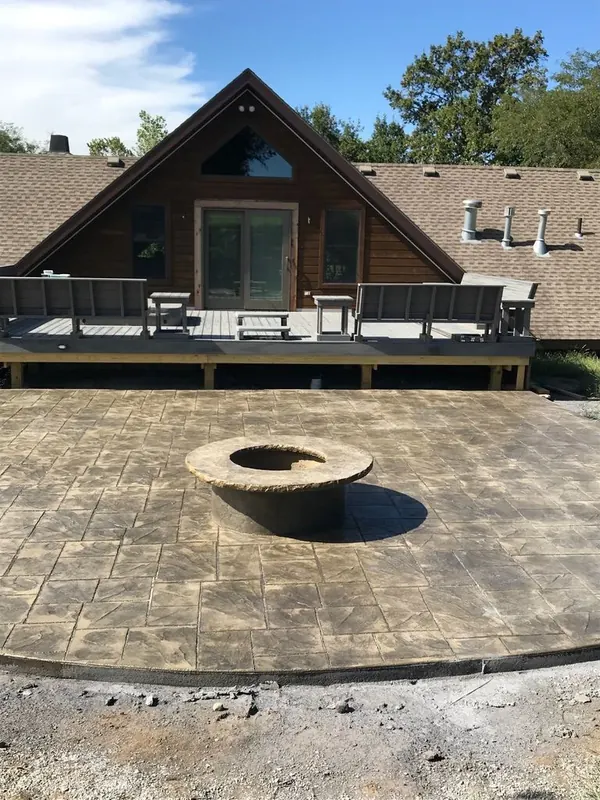 Stamped concrete patio with a built firepit surround alongside a home, poured with a decorative border
