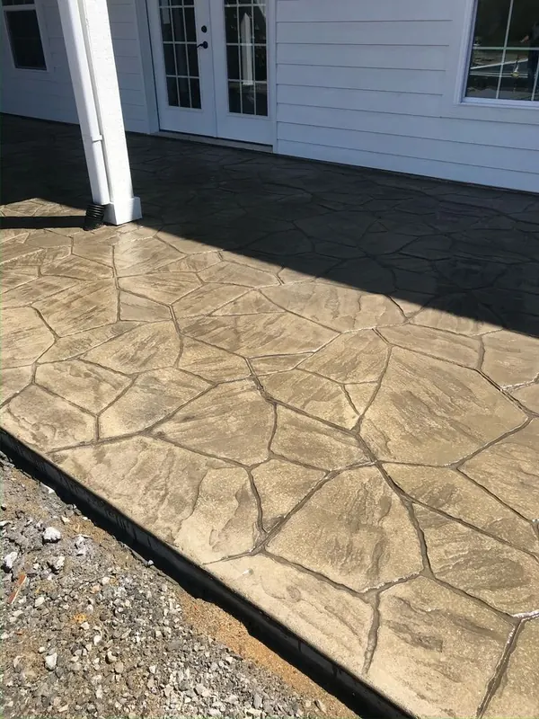 Stamped concrete patio in a random flagstone pattern finished in tan and buff tones with a darker antique release in the joints