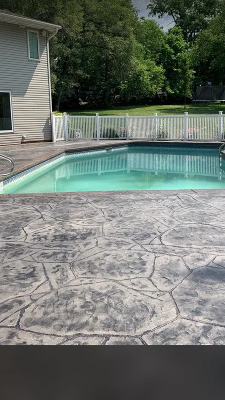 Stamped concrete pool deck in a flagstone pattern wrapping the coping, finished in light tones to stay cooler in Florida sun