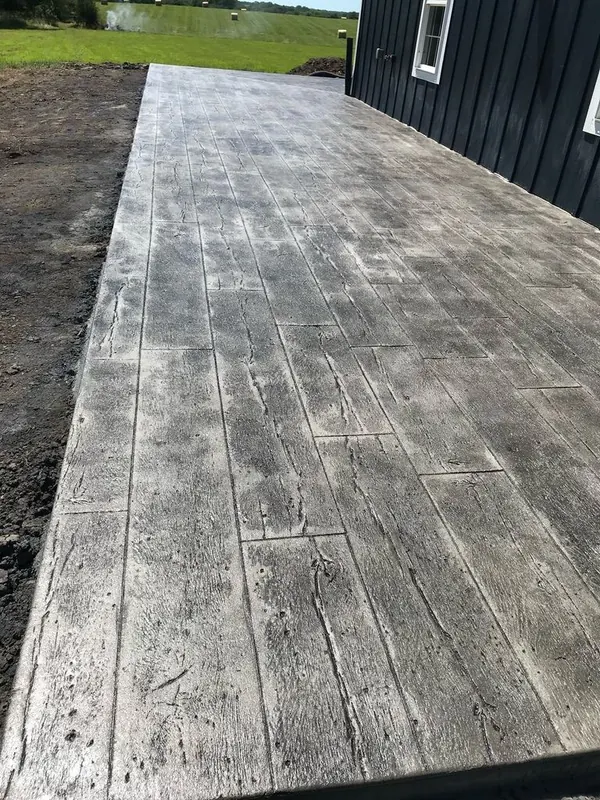 Wood-plank stamped concrete surface photographed down its length, showing consistent plank width and grain detail across the pour